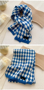 Detail of blue and white argyle knit scarf with Paris label on a textured surface