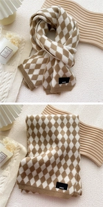 Detail of diamond pattern knit scarf with Paris label on a cozy warm-toned background