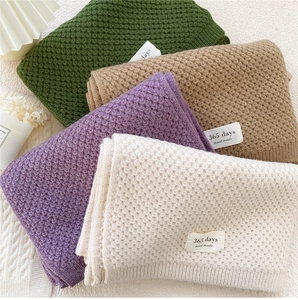 Detail of waffle-weave knitted scarves with handmade labels in four seasonal colors