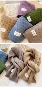 Close-up of knit scarf textures with handmade labels in multiple solid colors
