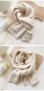 Detailed view of beige knitted scarf with honeycomb texture and 365 days handmade label