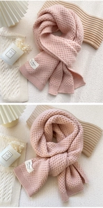 Detail of pink knit scarf showing wavy textured weave and hand made fabric label