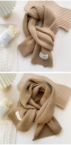 Detail of light brown waffle knit scarf featuring a white handmade woven label