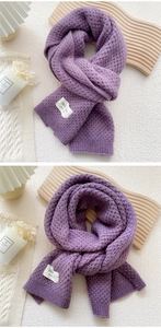 Detail of purple knitted scarf with pineapple stitch texture and white hand-made label