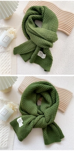 Detail of green waffle knit scarf featuring a white 365 days handmade woven label