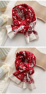 Detail of red and cream knitted scarf featuring festive snowflake patterns and ribbed edges