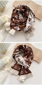 Detail of knitted winter scarf with brown snowflake patterns and a minimalist fabric label