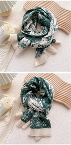 Detail of green and beige knit scarf featuring snowflake patterns and ribbed edges