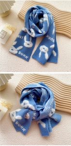 Close-up of blue knitted scarf featuring white bunny patterns and soft winter textures
