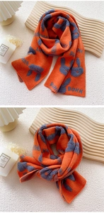 Close-up of orange knitted scarf with gray bunny jacquard pattern and textured finish