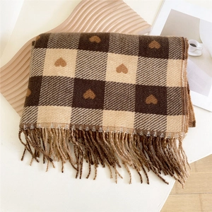 Détail d'une écharpe à carreaux avec motifs de cœurs et longues franges sur un plateau