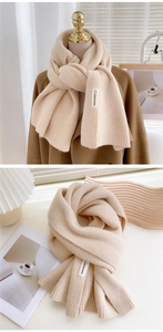 Détail écharpe tricotée beige avec bord côte et étiquette blanche sur manteau marron
