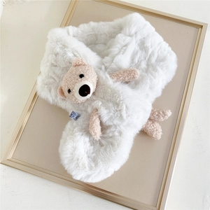Close-up of white plush scarf with a brown teddy bear ornament and washing label detail