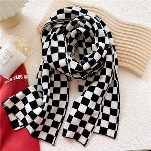 Détail de l'écharpe en tricot à damier noir et blanc montrant la texture douce de la laine