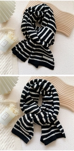 Détail d'une écharpe en maille rayée noir et blanc avec étiquette tissée minimaliste