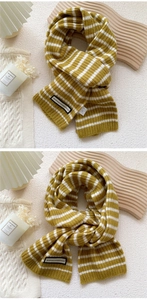 Détail d'une écharpe en maille rayée jaune et beige avec étiquette alphabet et texture douce