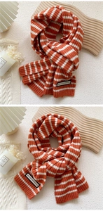 Détails de la maille d'une écharpe d'hiver à rayures orange et blanches avec écusson