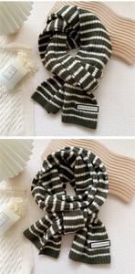 Gros plan sur une écharpe en tricot à rayures vert et beige avec étiquette en tissu