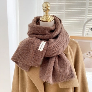Chunky knit brown scarf with classic cable stitch pattern shown on a wool coat