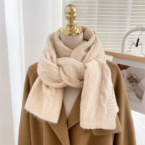 Detail of apricot knit scarf showing chunky cable stitch pattern and soft texture