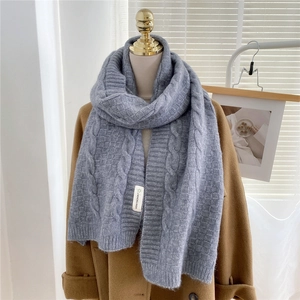 Detailed close-up of thick cable knit pattern on gray winter scarf over wool coat