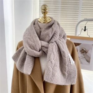 Detailed cable knit pattern on thick oat-colored winter scarf with brand woven label