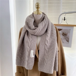Close-up of thick cable knit winter scarf in taupe color on a beige wool coat