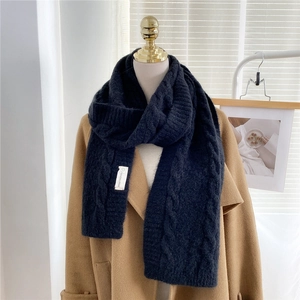 Close-up of black cable knit scarf with brand label on soft thick cashmere-like material