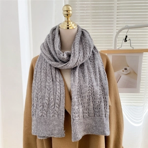 Detail of cable-knit grey winter scarf with ribbed ends styled on a camel wool coat