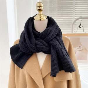 Close-up of thick black chunky knit scarf with intricate cable knit texture and warm weave