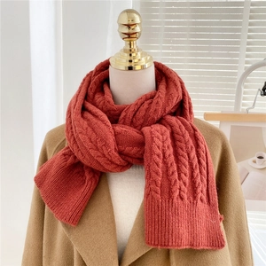 Thick brick red cable knit scarf for winter shown on a mannequin with khaki coat