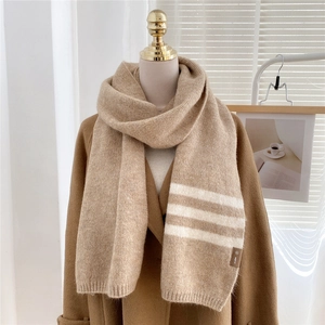 Thick beige knitted scarf with white stripes and label displayed on a mannequin
