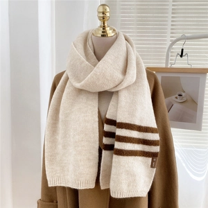 Detail of soft cream knitted scarf with brown stripes and small leather brand tag