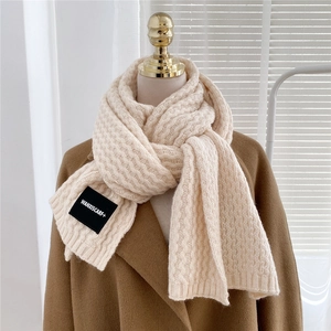 Thick cream knit scarf with wavy texture on a mannequin with a brown winter coat