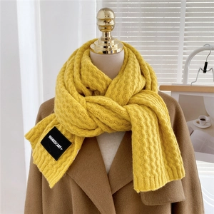 Detail of chunky ginger yellow knit scarf with woven texture and premium brand label