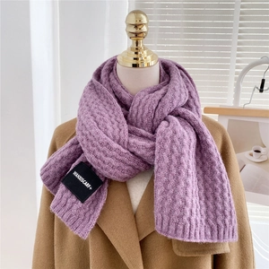 Detail of purple ribbed knit scarf texture and brand label on a beige wool coat