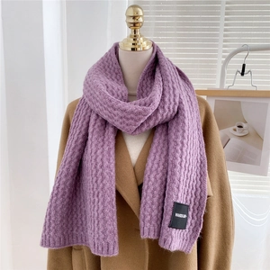 Detail view of purple knit scarf with vertical texture and branded label on coat