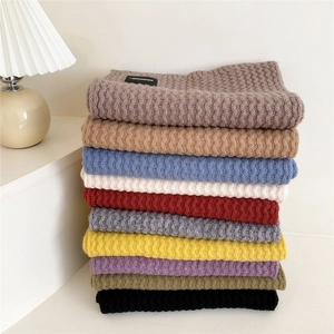Thick knitted scarves in various colors stacked vertically with premium ribbed texture