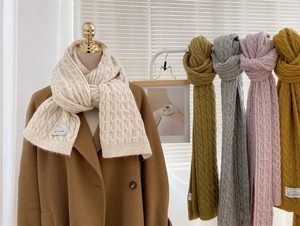 Detailed macro view of the thick knit cable pattern and leather label on the soft winter scarf