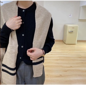 Detail of beige striped knit shawl paired with black cardigan for cozy winter layering