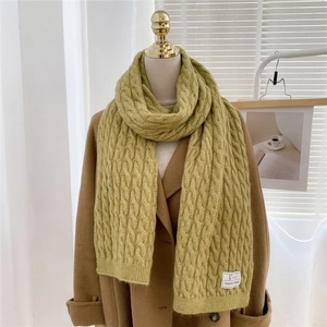 Close-up of olive green thick knit scarf with chunky cable stitch and woven brand label