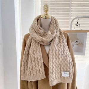 Detailed close-up of beige cable knit scarf texture on a brown wool coat display