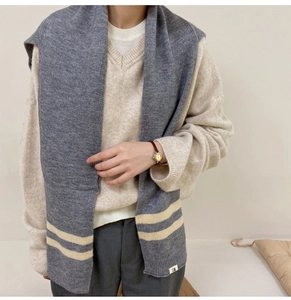 Detailed texture of thick grey knitted shawl scarf with beige stripes and brand label