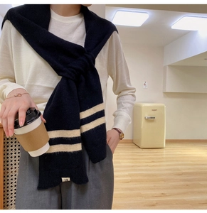 Detail of navy knit scarf with beige stripes showing wool texture and soft fabric finish