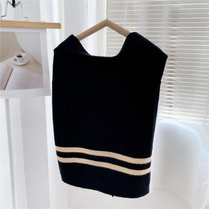 Detail of a black knitted shoulder wrap featuring dual white stripes on the bottom hem