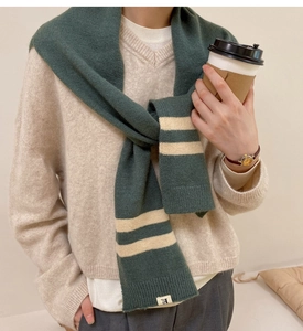 Close-up of dark green striped knit shawl with soft texture and small brand patch