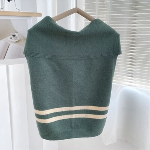 Detail of green knitted shawl with white stripes on a wooden hanger with natural light