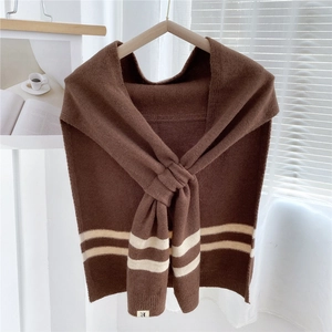 Macro shot of striped brown knit shawl featuring cross-loop style on wooden hanger