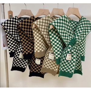 Detail view of checkered knit scarves in four colors with smiley face brand tags