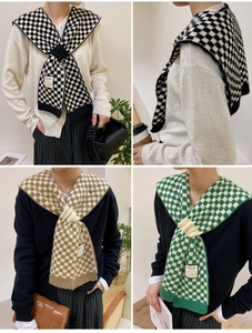 Detailed view of knitted checkerboard shawl featuring a brand label and ribbed edge texture